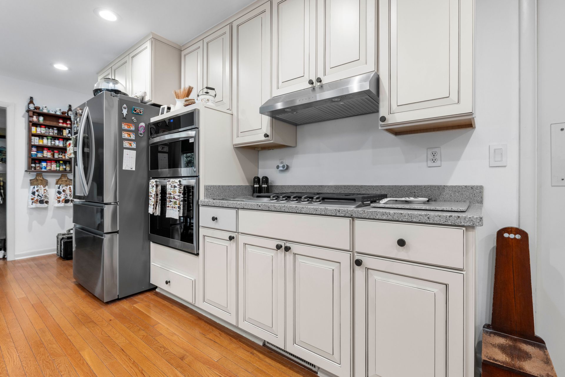 Kitchen with white cabinets, stainless steel appliances, and wooden floor.