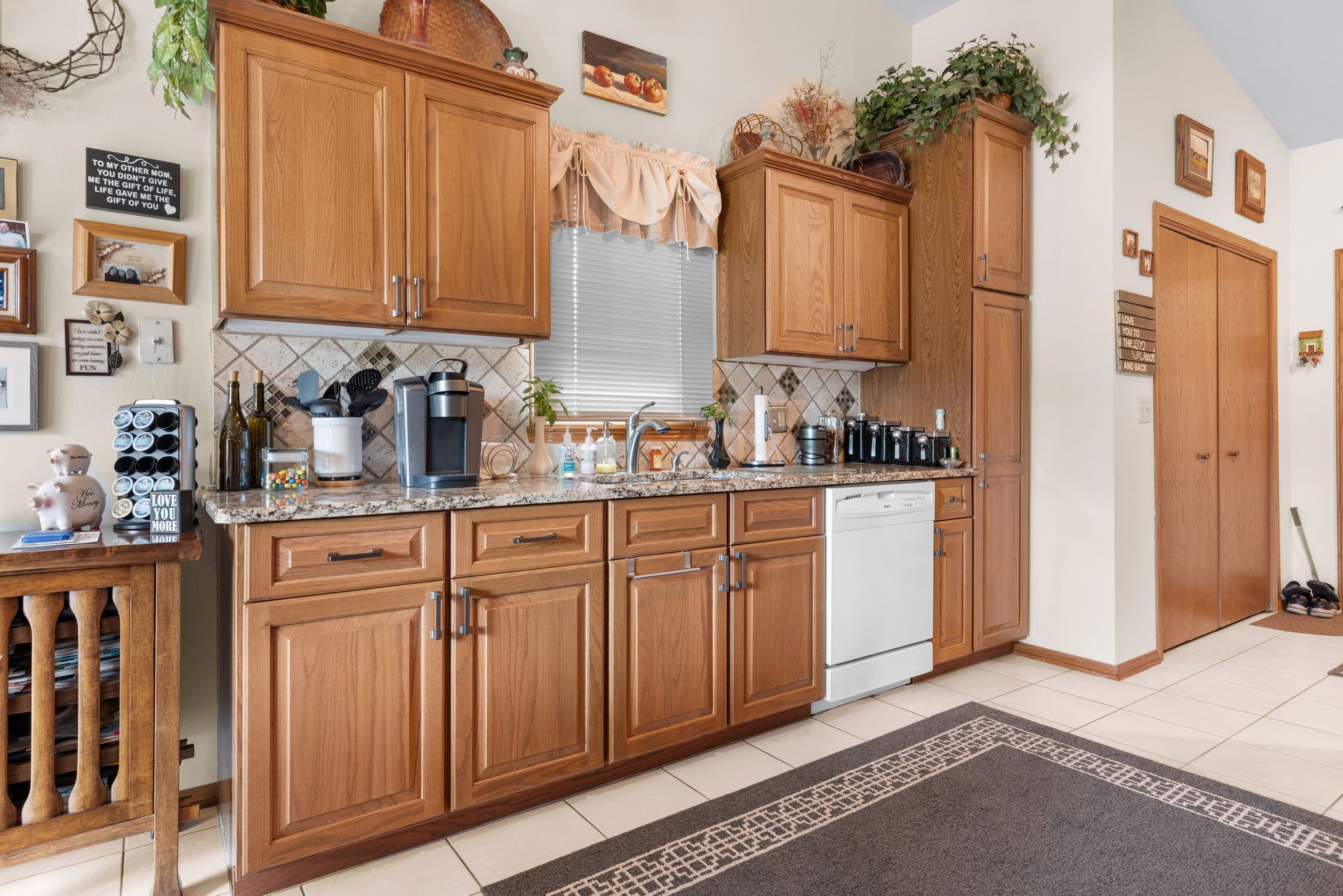 Kitchen with wooden cabinets, granite countertops, white appliances, and tiled backsplash.