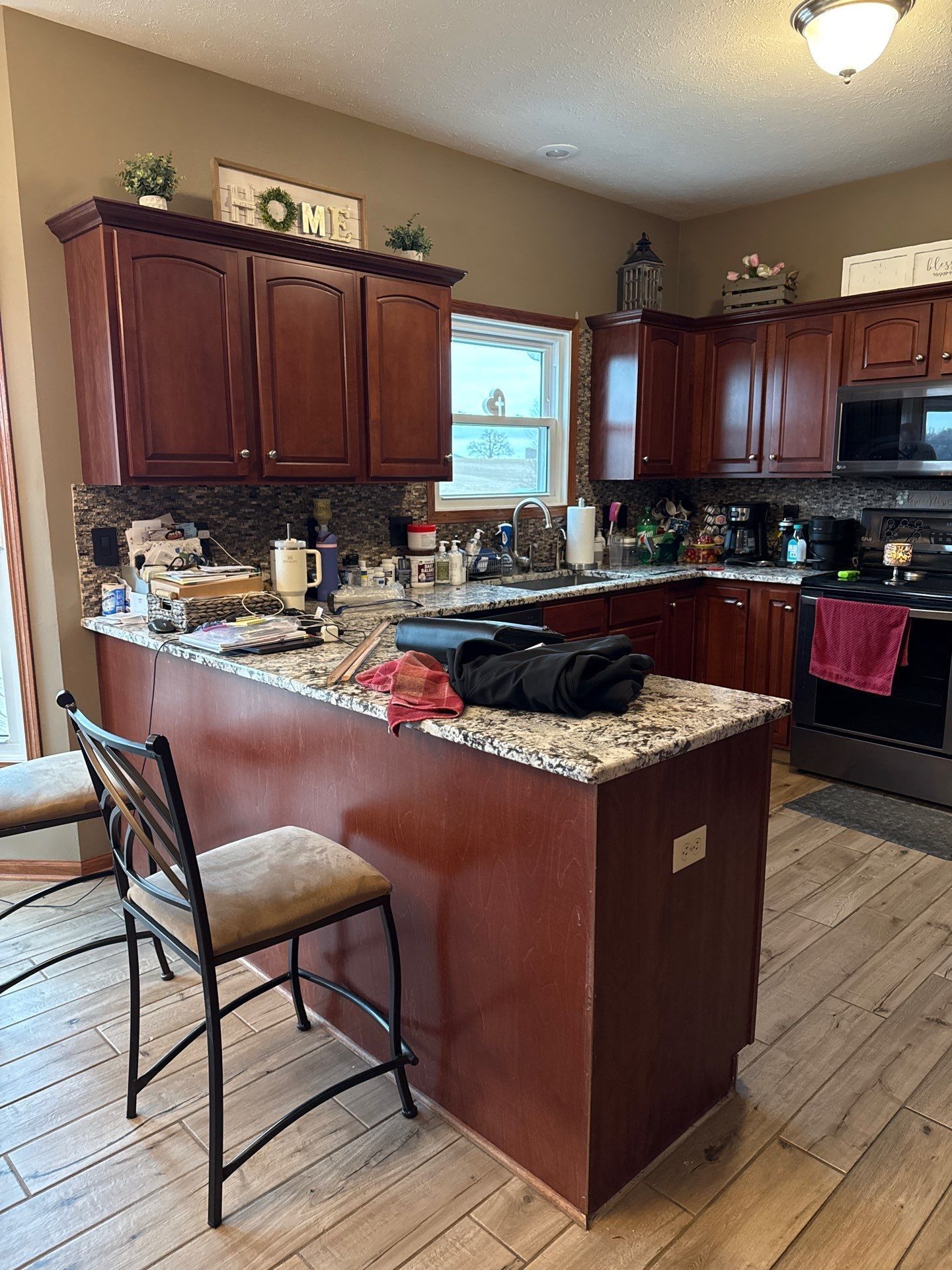 Kitchen with brown cabinets, granite countertops, and an island with a bar stool.