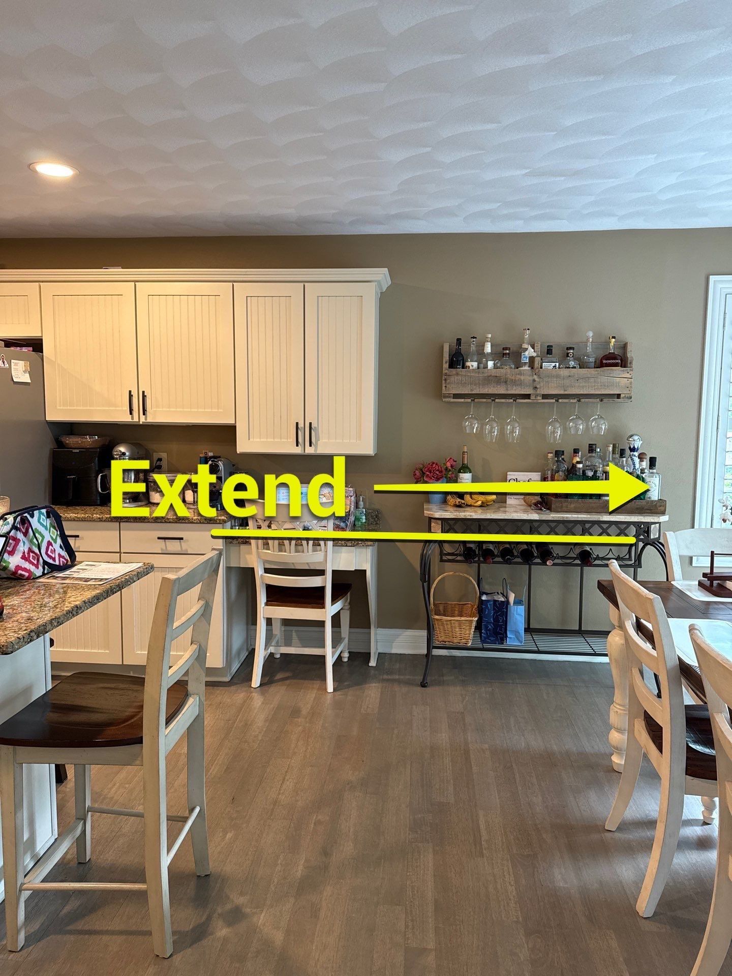 Kitchen with light cabinets, bar table, and dining table. Yellow