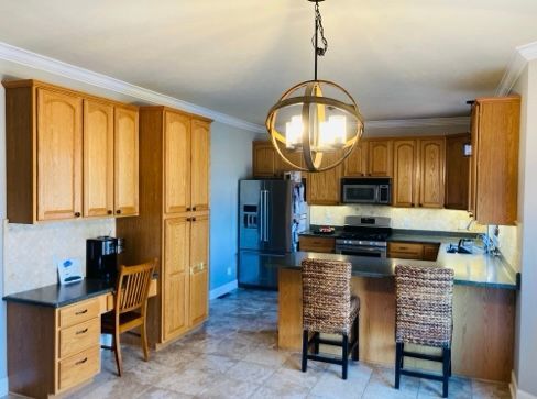 Kitchen with light wood cabinets, stainless steel appliances, and a central island with two bar stools.