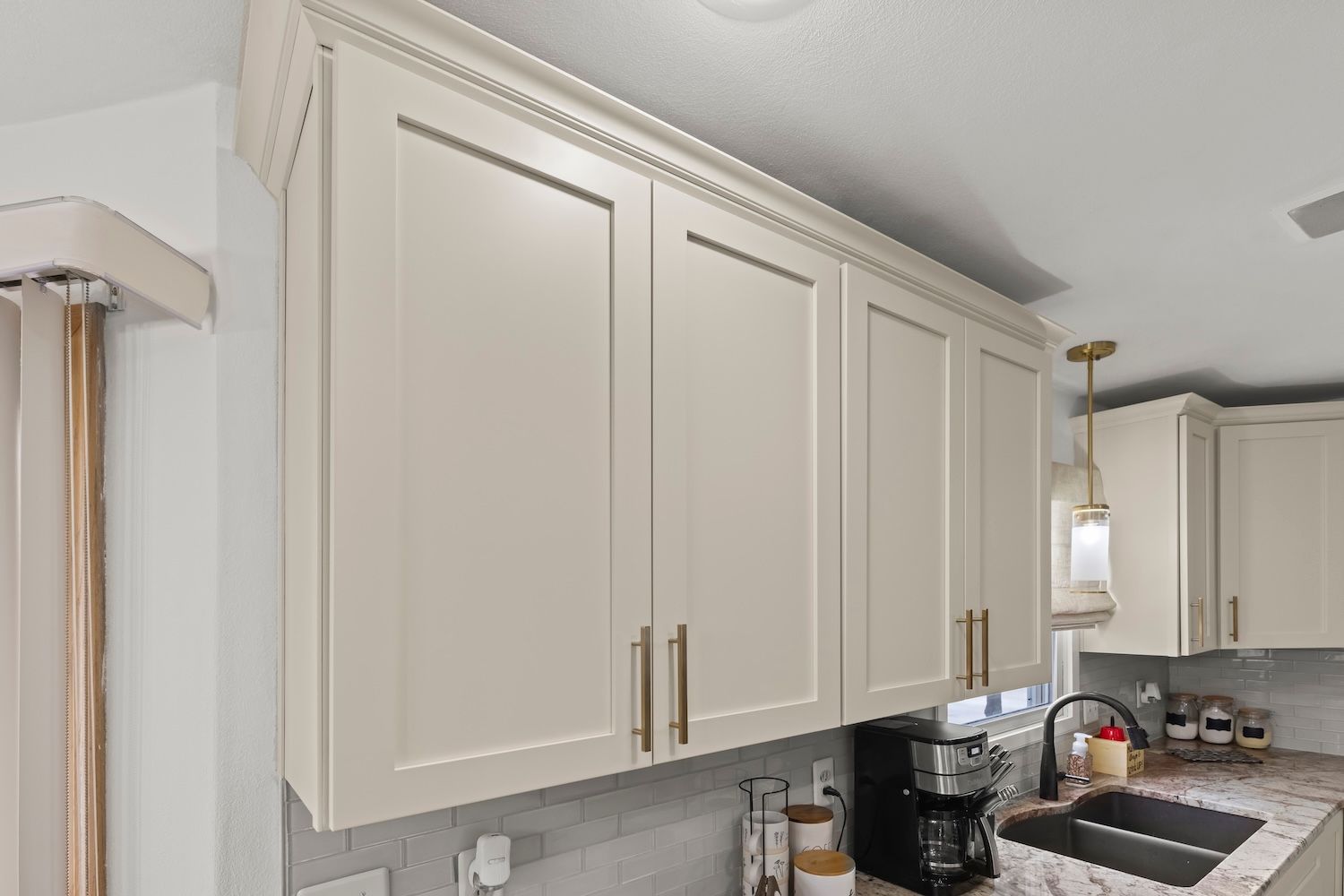Cream-colored kitchen cabinets with gold handles, above a counter.