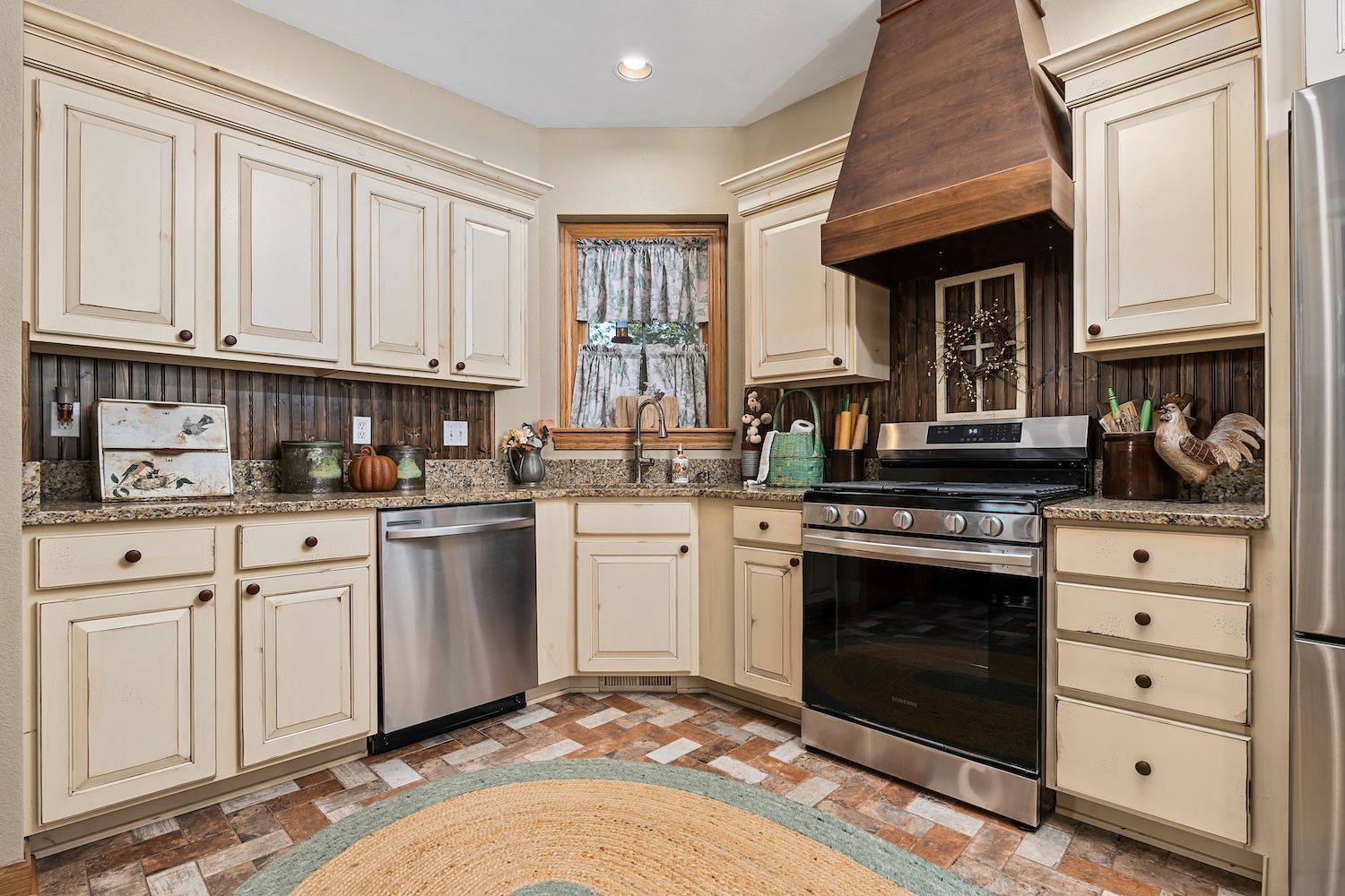 Cream-colored kitchen with stainless steel appliances, granite countertops, and a copper range hood.