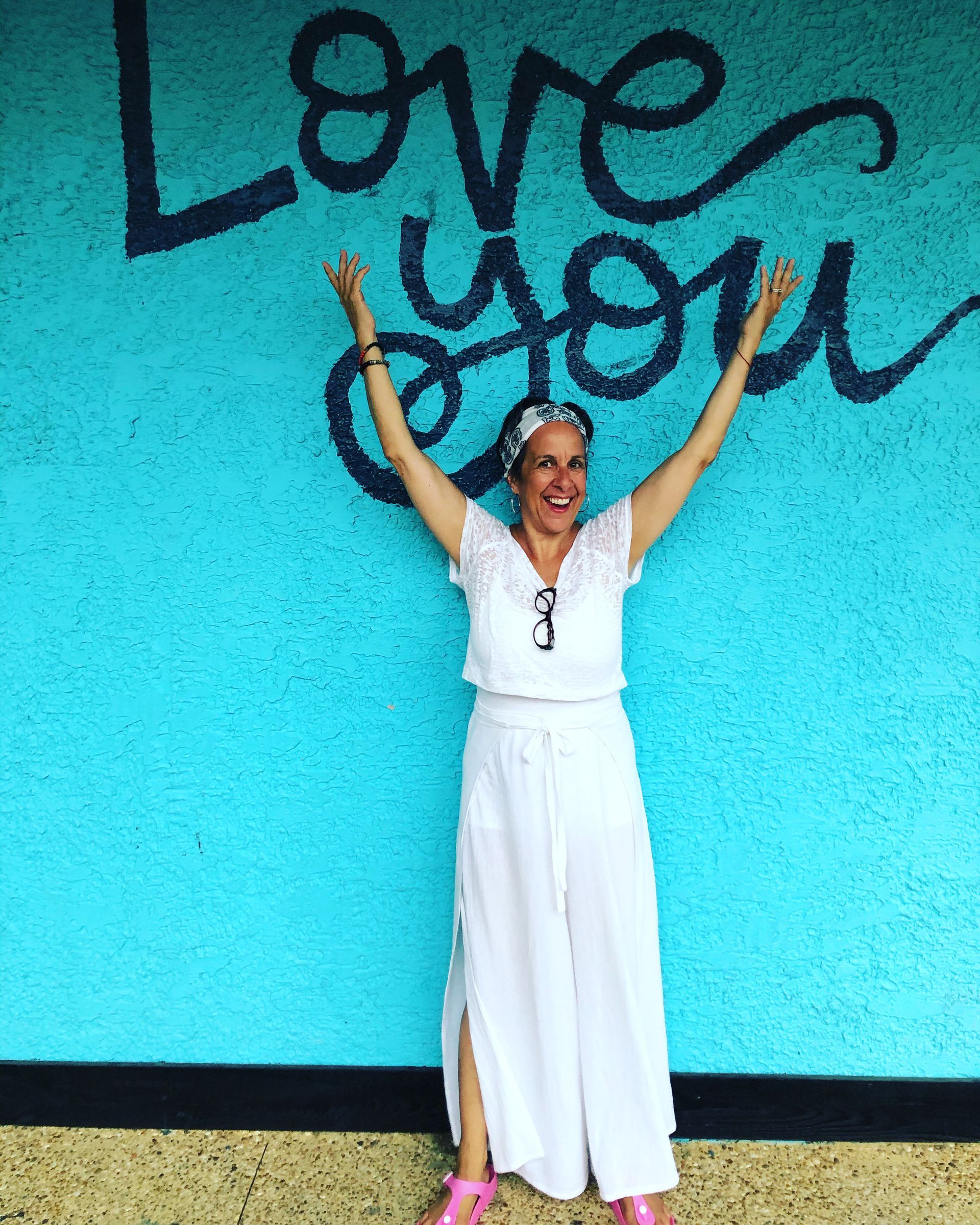 A woman is standing in front of a wall that says love you