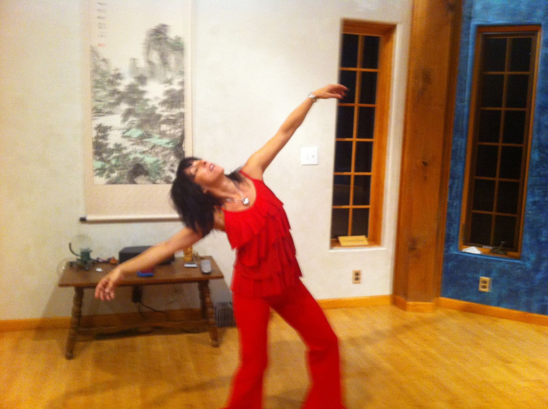 A woman in red pants is dancing in a room