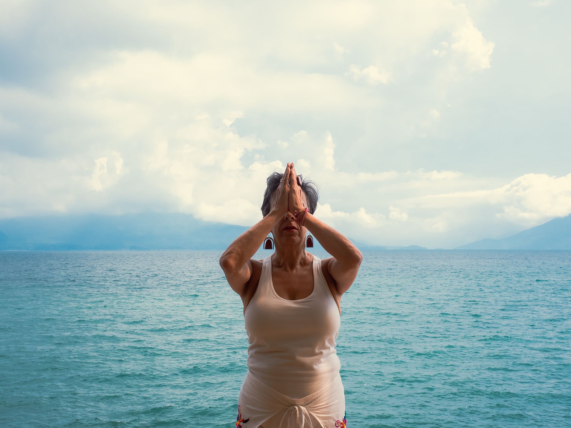 A woman is doing yoga on the beach near the ocean.