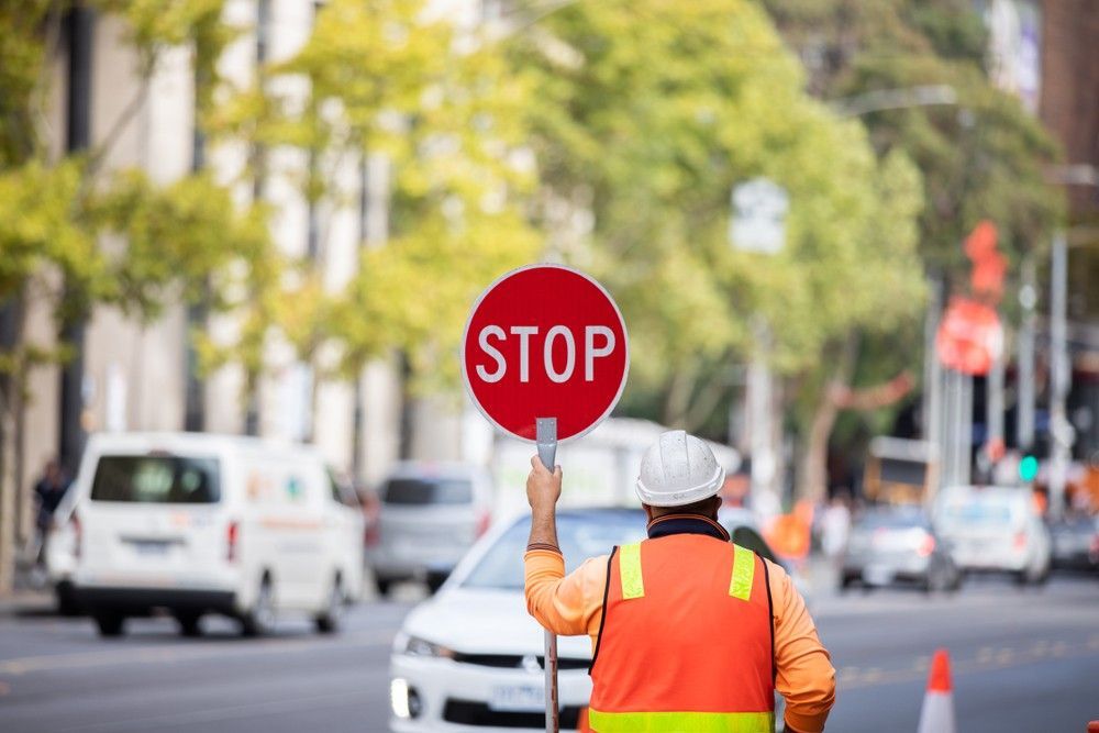 A Man is Holding a Stop Sign on a City Street — Payton Civil Products in Roma, QLD