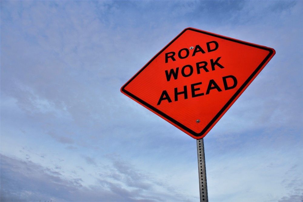 An Orange Road Work Ahead Sign Against a Blue Sky — Payton Civil Products in Wilsonton, QLD