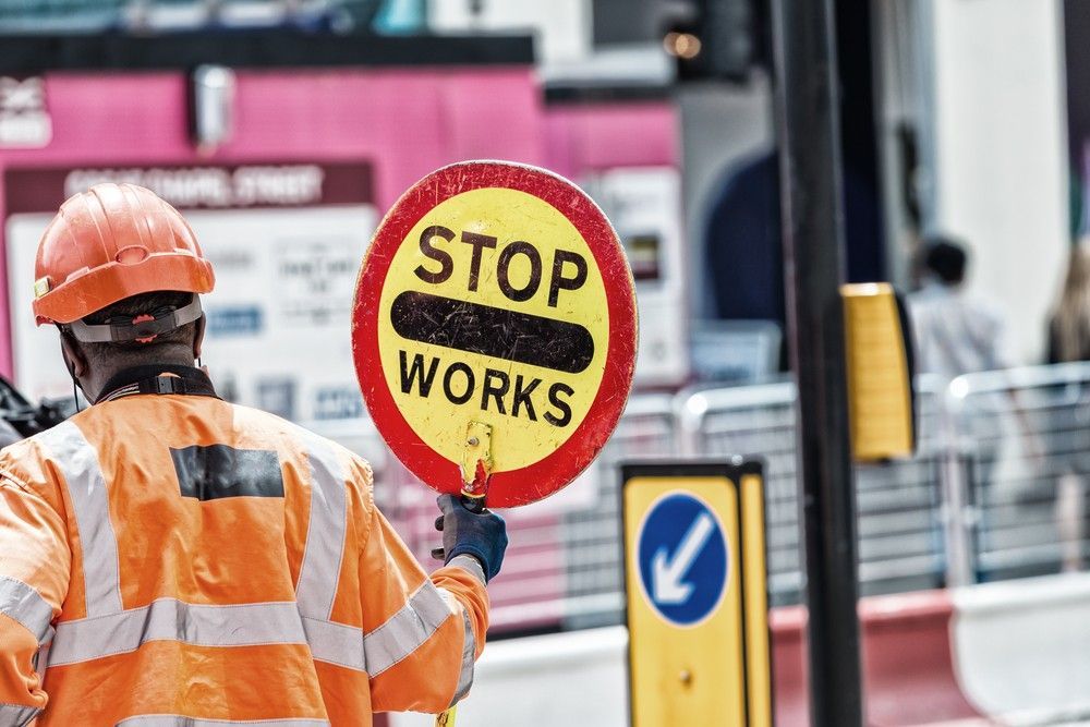 A Construction Worker is Holding a Stop Works Sign — Payton Civil Products in Gatton, QLD