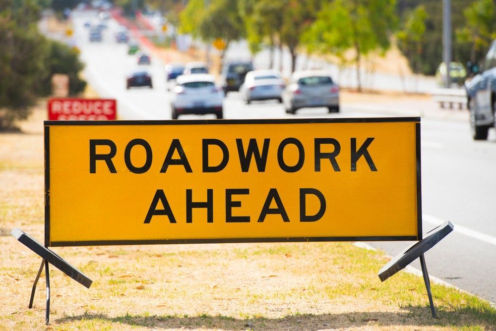 A Yellow Roadwork Ahead Sign is Sitting on the Side — Payton Civil Products in Wilsonton, QLD