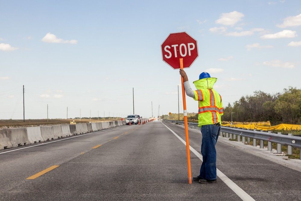A Man is Holding a Stop Sign on the Side of a Highway — Payton Civil Products in Wilsonton, QLD