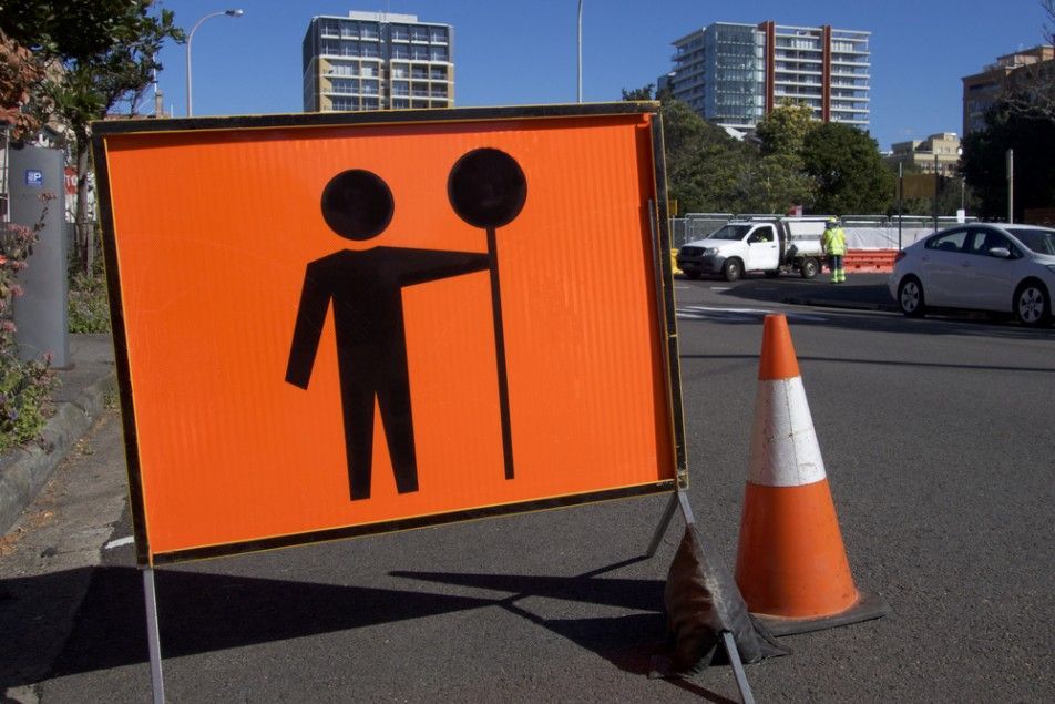 An Orange Sign With a Man Holding a Stop Sign — Payton Civil Products in Kingaroy, QLD