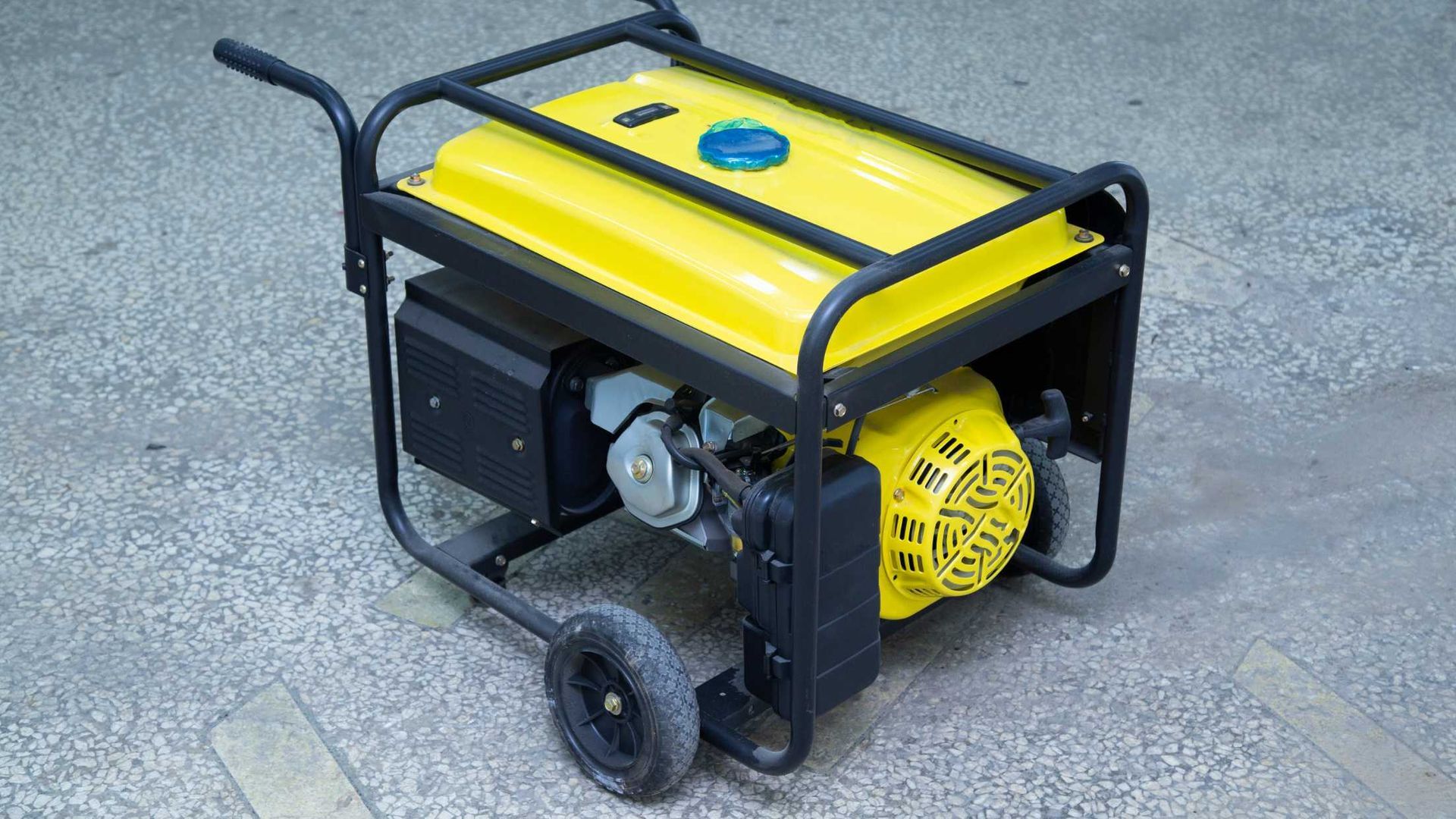 A yellow generator is sitting on a cart on the ground.