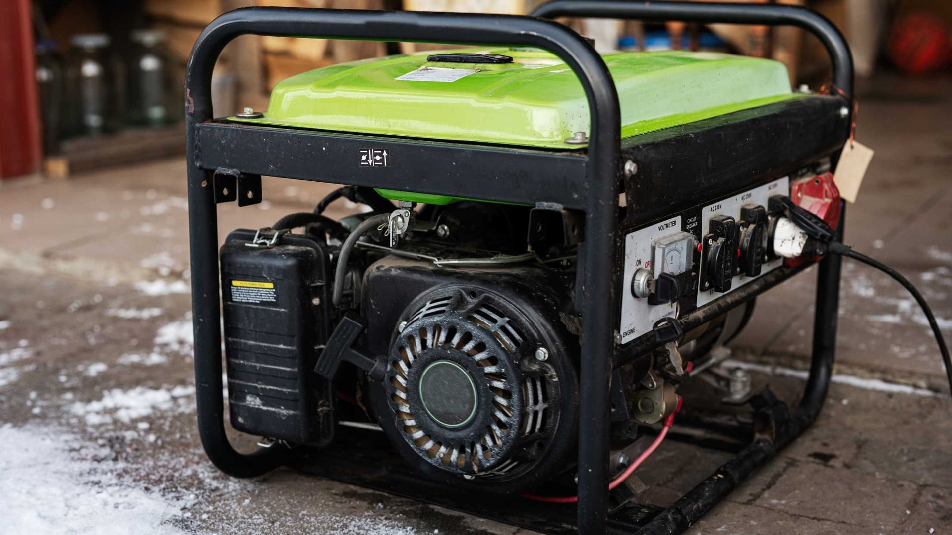 A green and black generator is sitting on the ground in a garage.