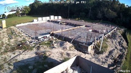 Obra con cimientos. Hormigón, varillas corrugadas y encofrado de madera en proceso. Exterior soleado.