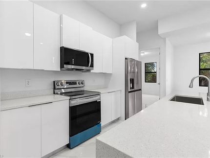 Cocina blanca moderna con electrodomésticos de acero inoxidable y encimeras claras.