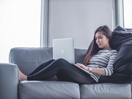 Poor posture created by working on a lap top on the settee. Photo courtesy of mimi-thian-BYGLQ32Wjx8-unsplash