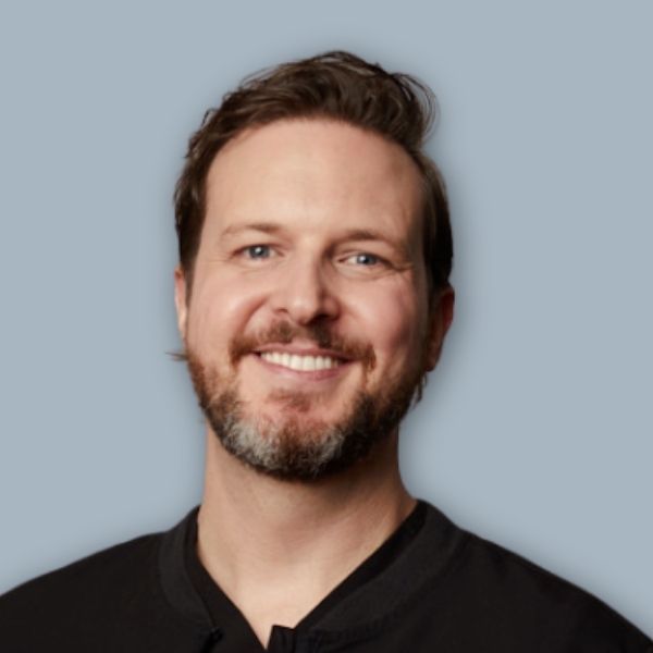 A man in a suit and white shirt is smiling