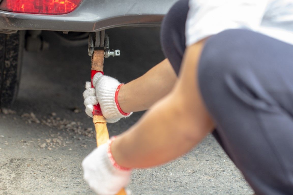 Person in gloves using a jack to lift a car.