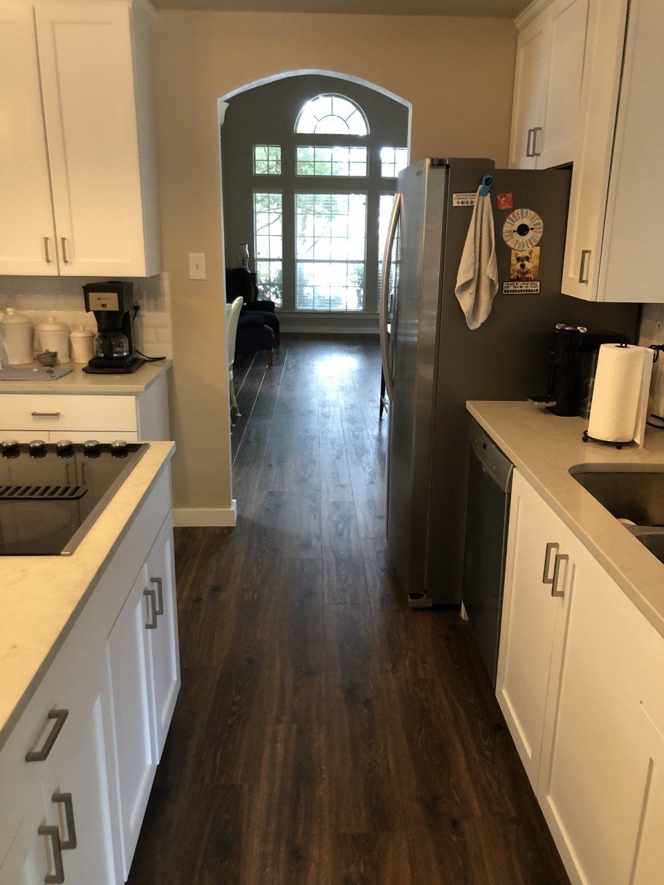 A kitchen with white cabinets and a stainless steel refrigerator
