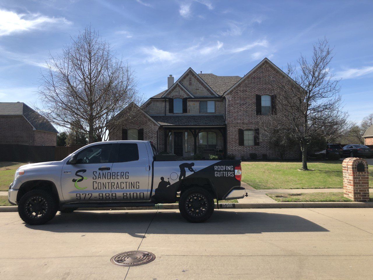 A white truck is parked in front of a large brick house.