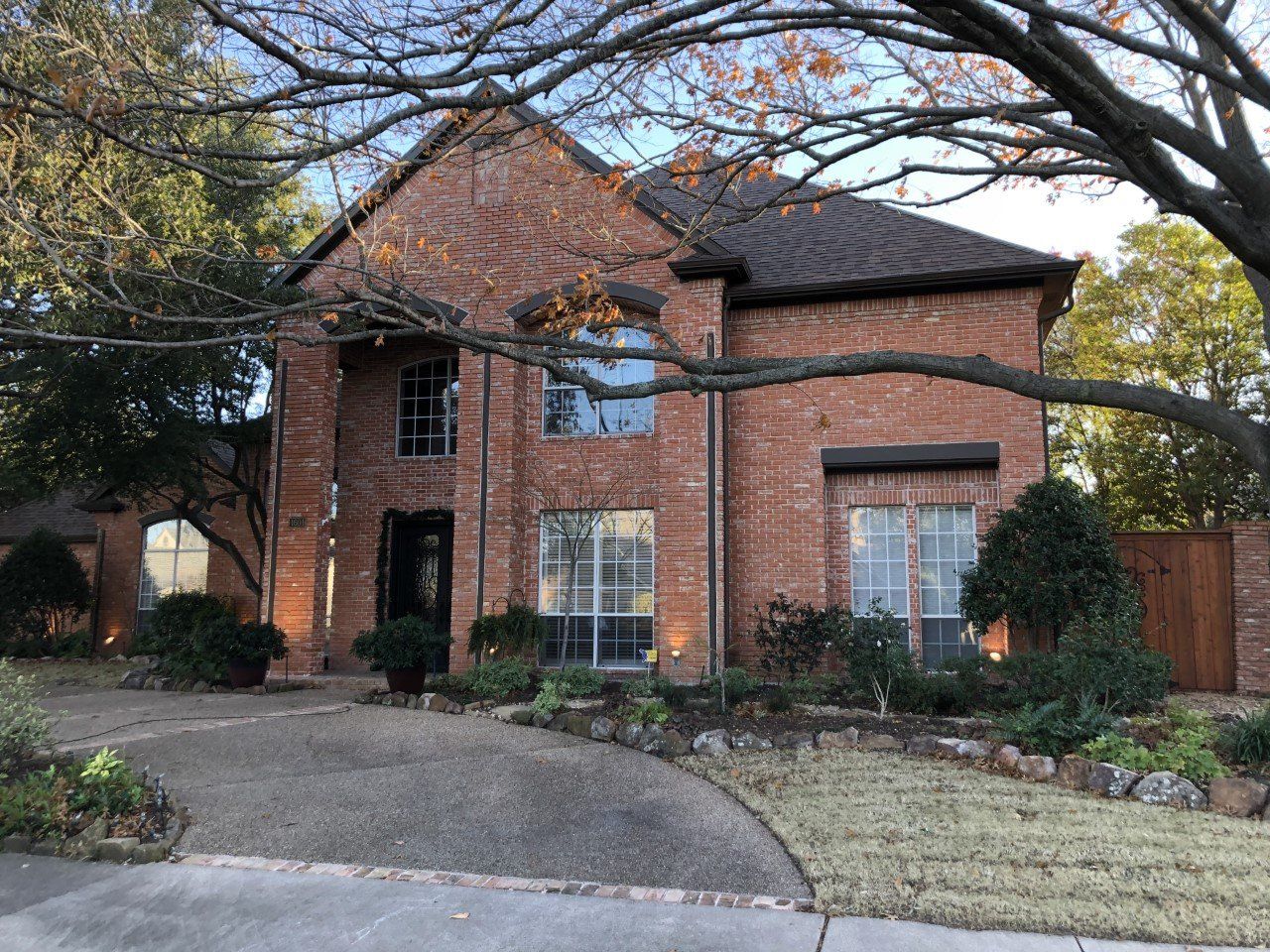 A large brick house with a lot of windows and a tree in front of it.