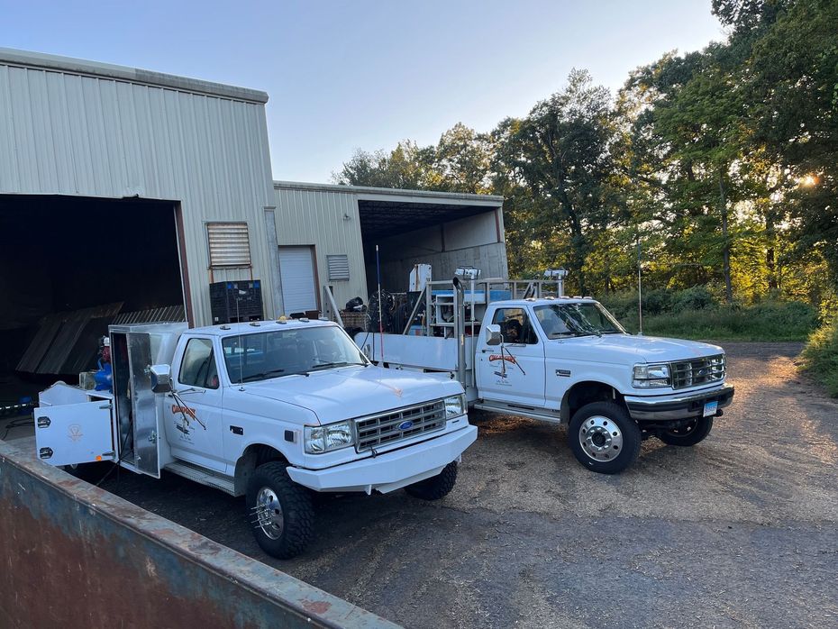 Two white trucks are parked in front of a building.