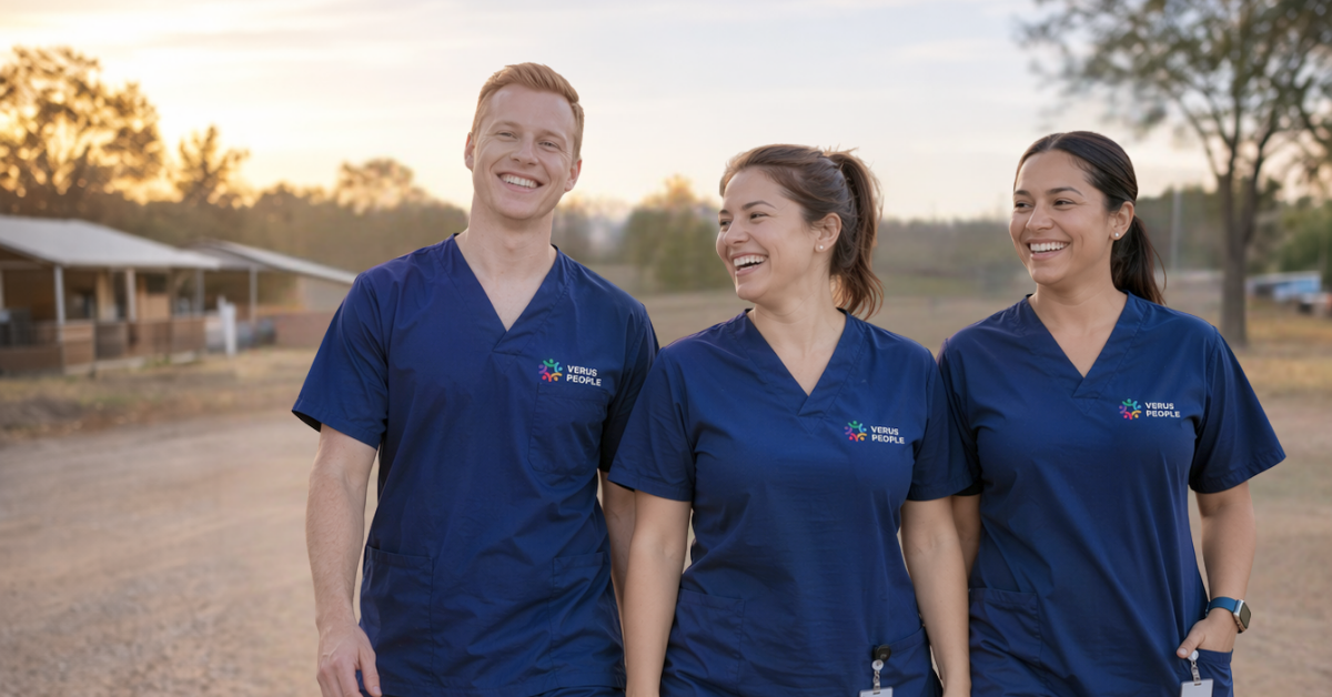 Three healthcare workers in navy scrubs walking together outdoors at sunset, smiling