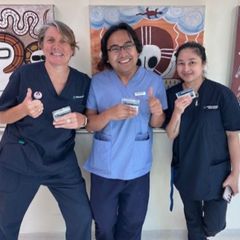 A man and two women giving a thumbs up in front of a painting