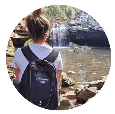 A woman with a backpack is looking at a waterfall