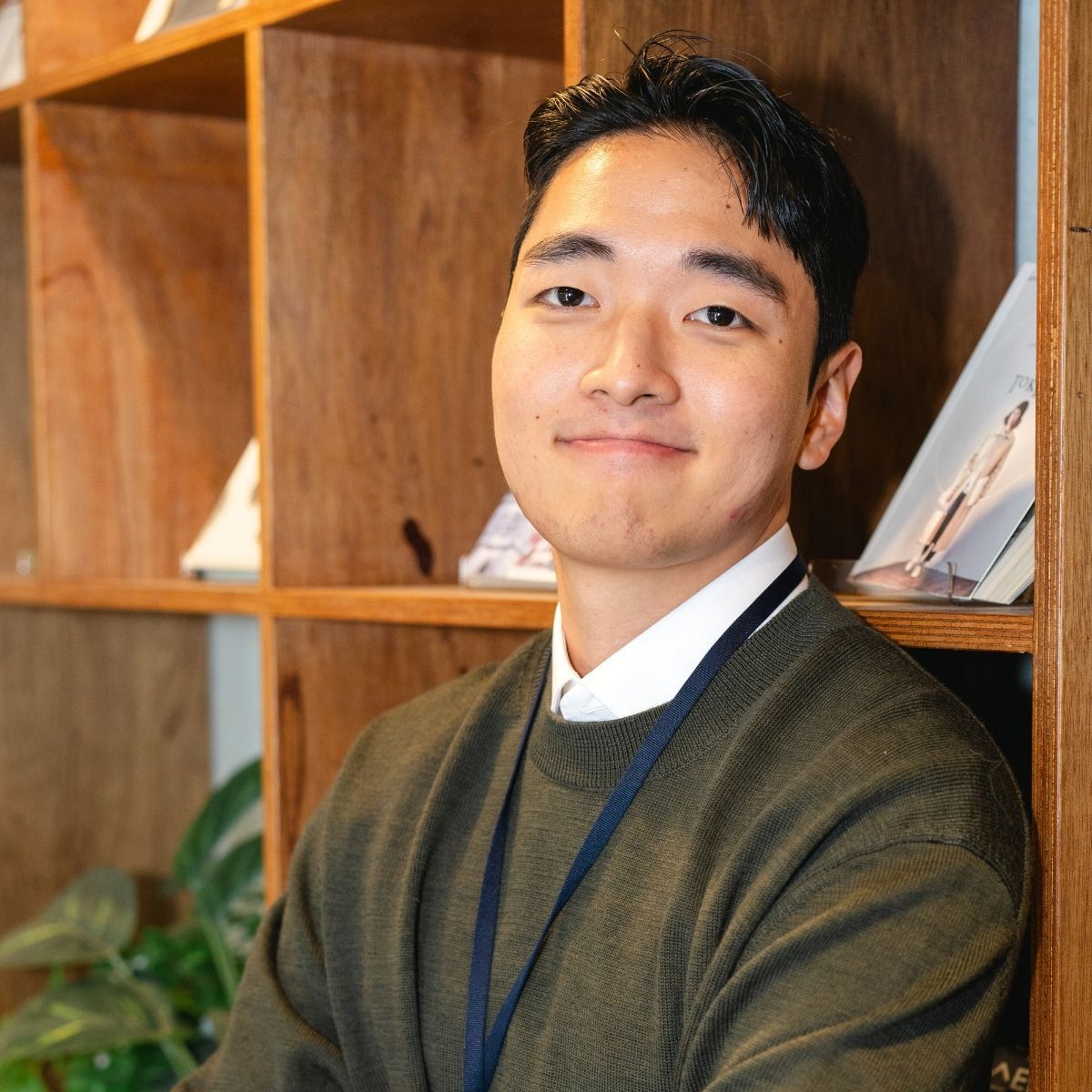 Smiling healthcare worker in blue scrubs with arms crossed, in a medical setting.