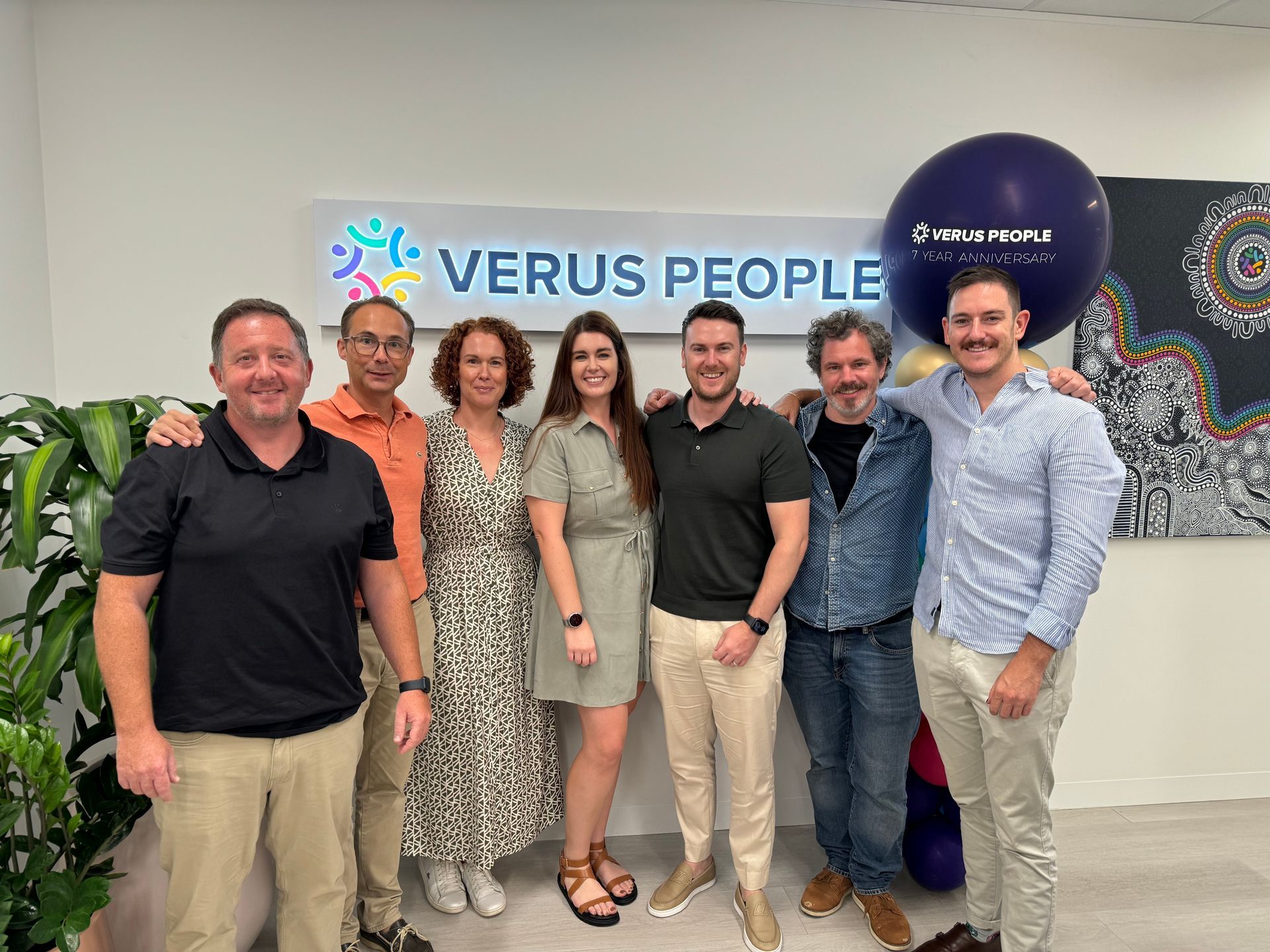 A group of people standing in front of a sign that says verus people