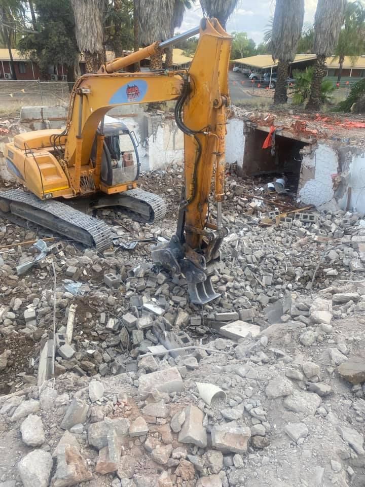 A yellow excavator is sitting on top of a pile of rocks. — Bullant Building In Ciccone, NT