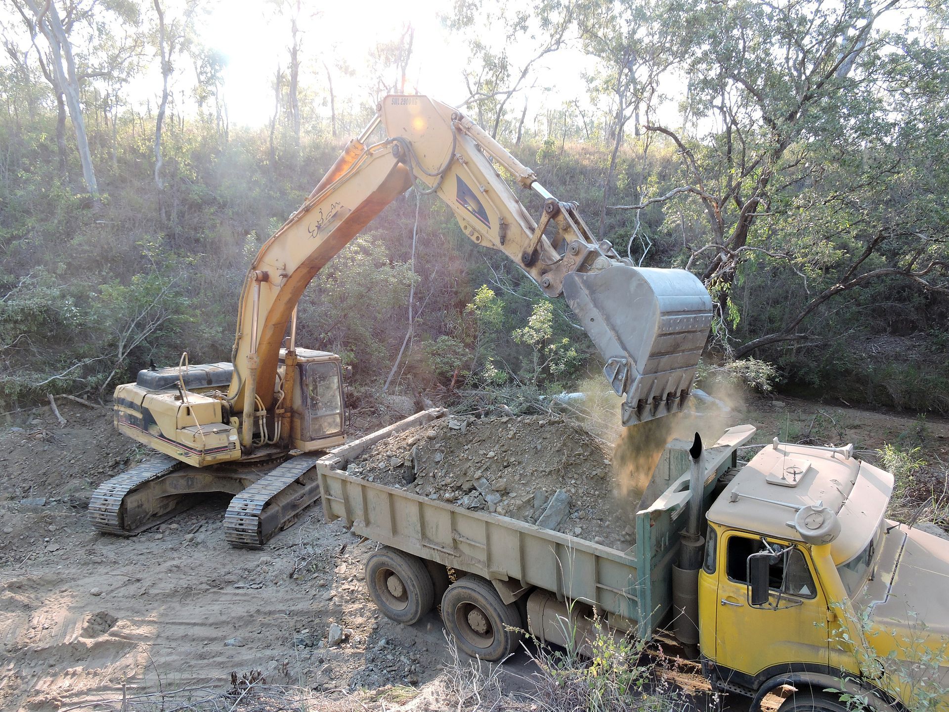 An excavator is loading dirt into a dump truck.