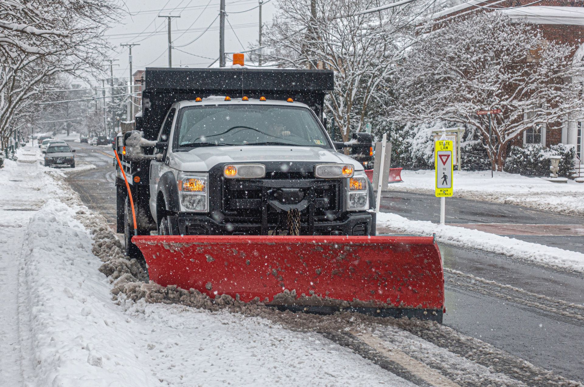 A snow plow is clearing snow from the side of the road.
