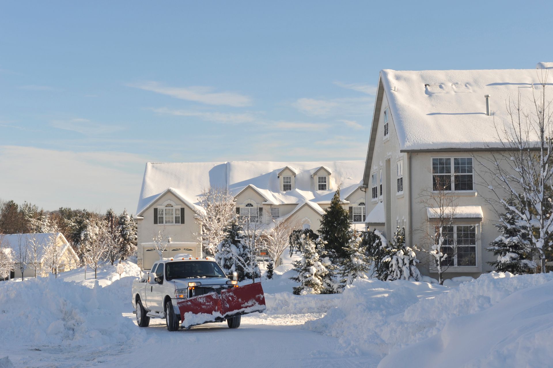 A snow plow is driving down a snow covered street