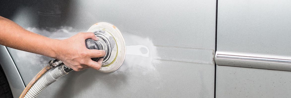 A person is sanding a car with a sander.
