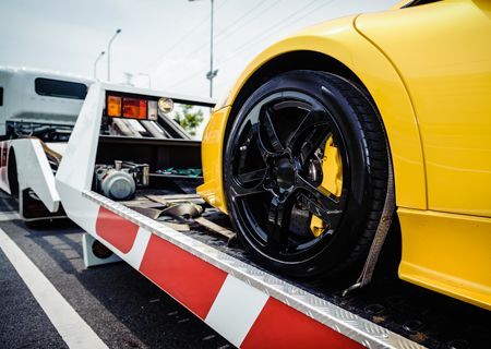 A yellow sports car is being towed by a tow truck.