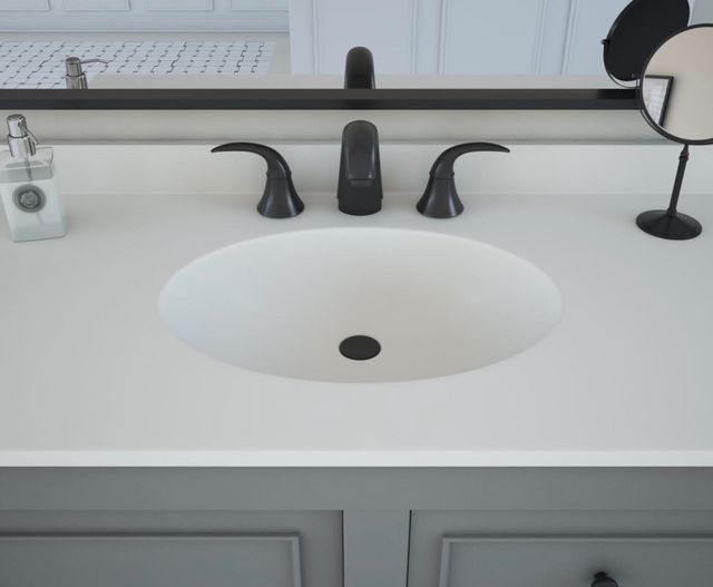 White bathroom sink with black faucet and soap dispensers on a countertop mirror.