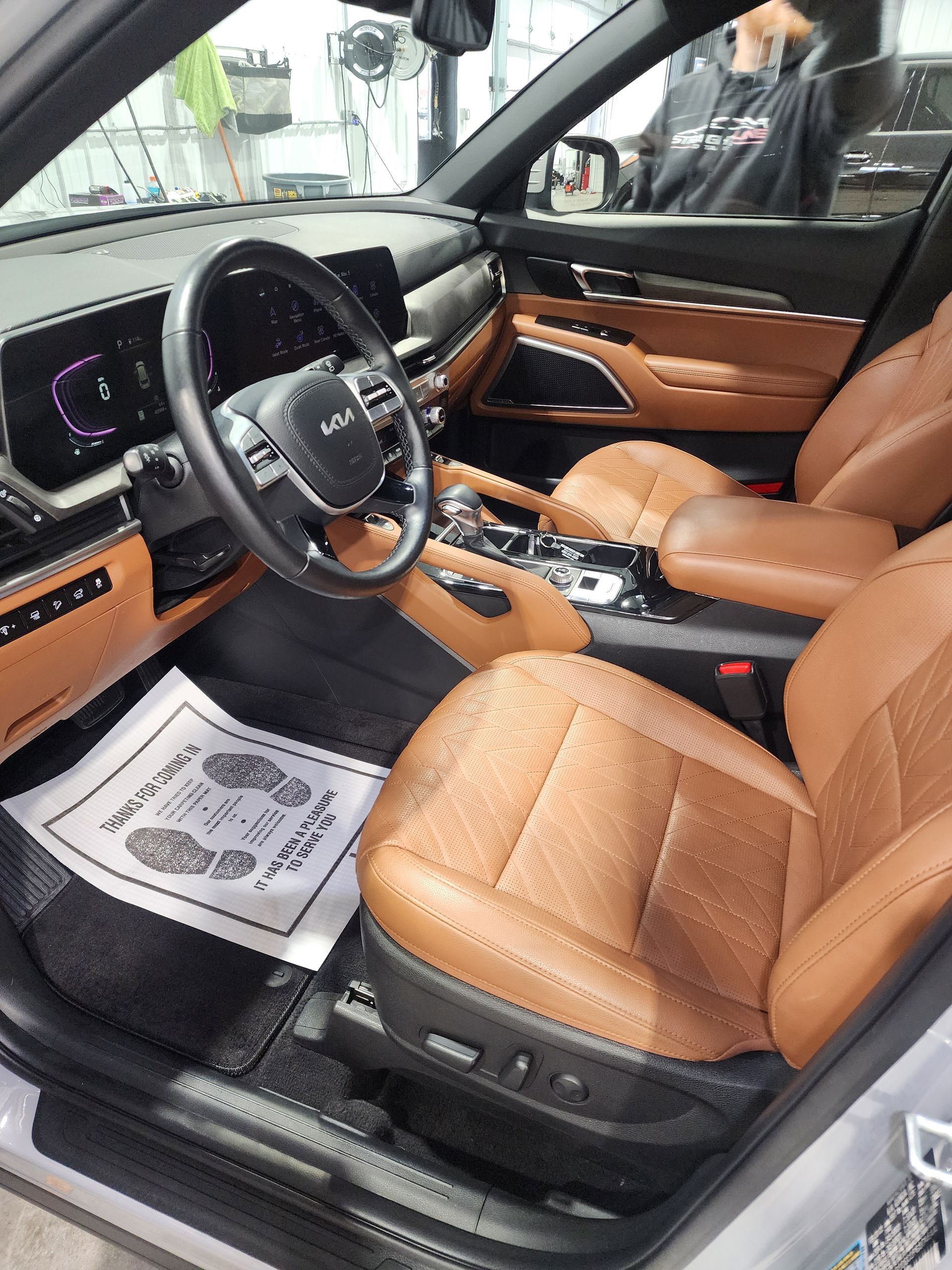 The interior of a silver car with brown leather seats and a steering wheel.