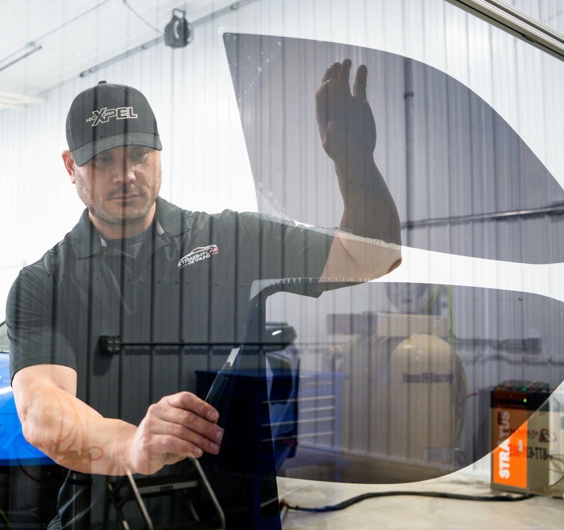 A person is applying tinted glass to a car window.