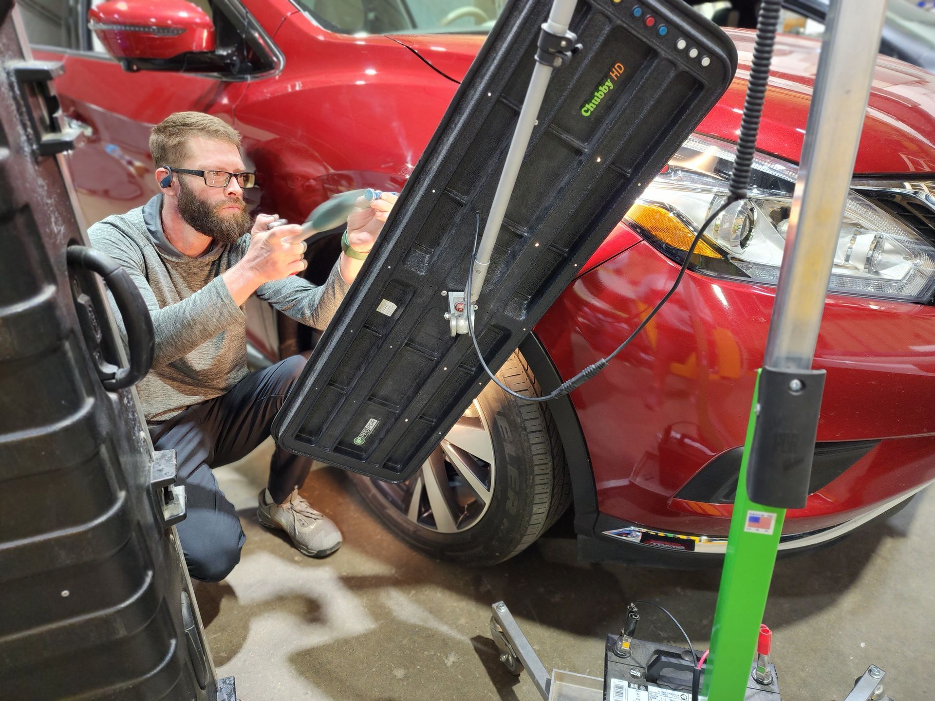 A man is cleaning the wheel of a black car with a sponge.