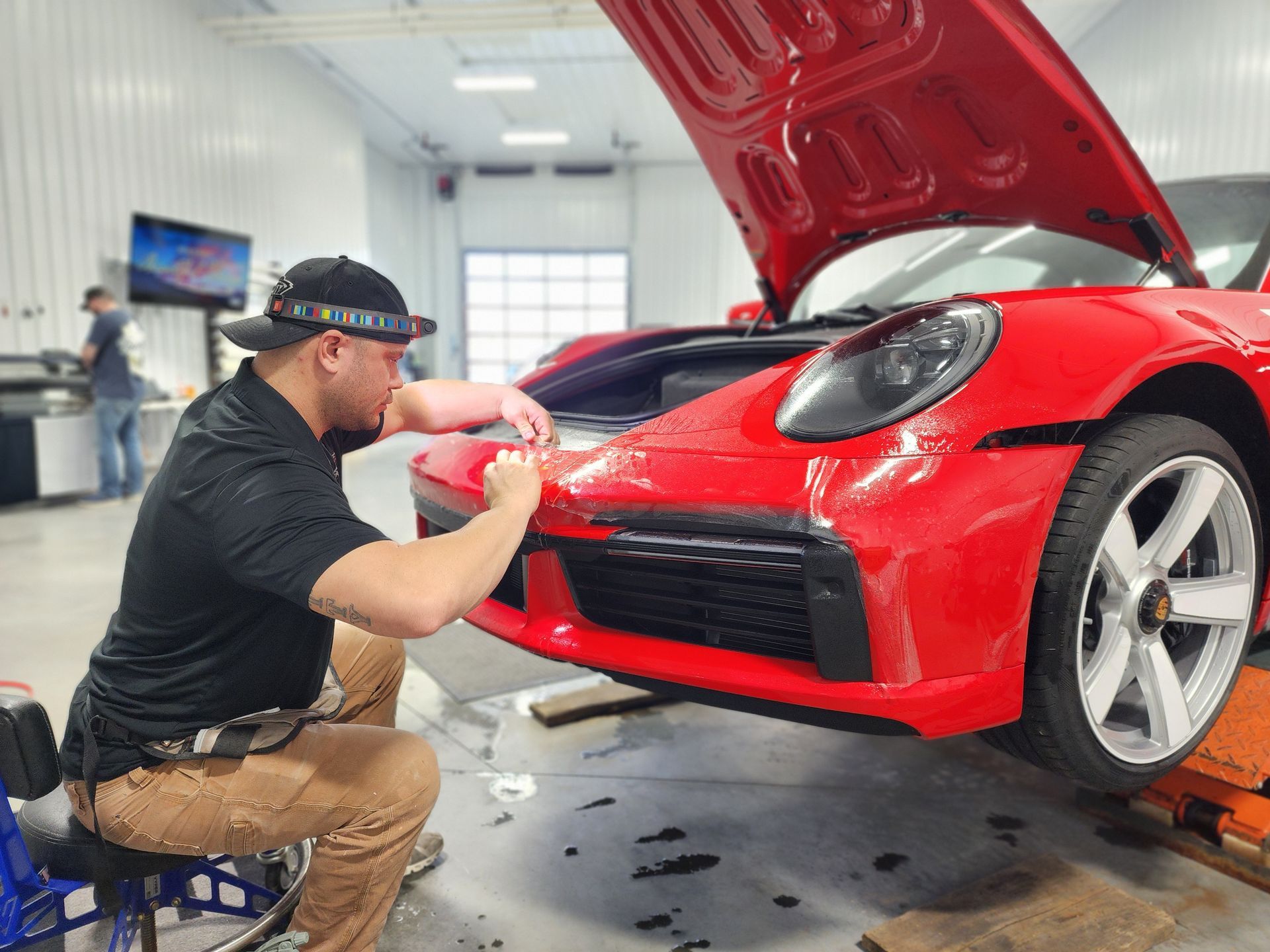 A man is working on a red sports car in a garage.