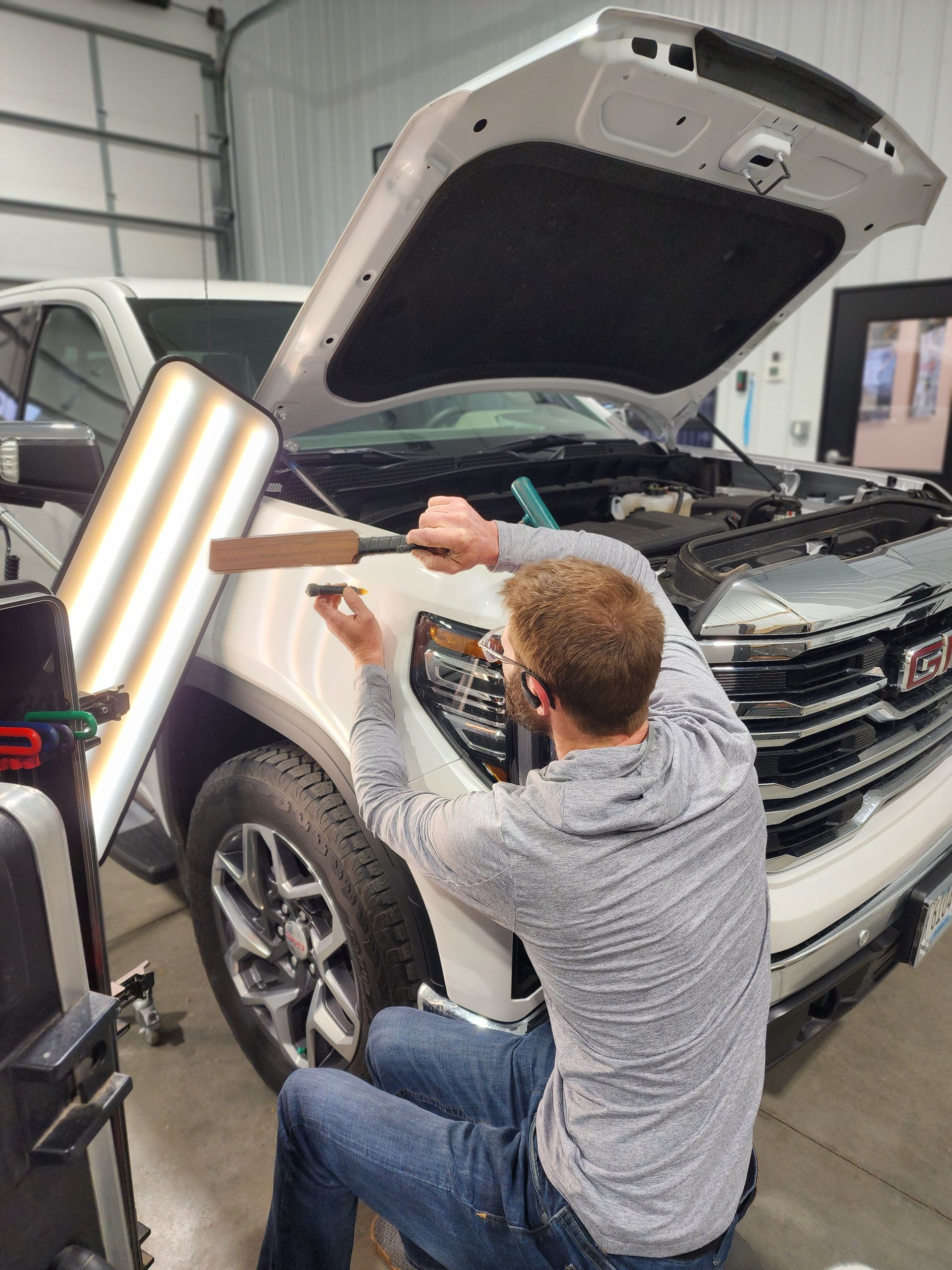 A man is working on the hood of a truck.