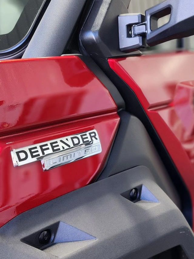 A person is using a blue squeegee to remove plastic from the hood of a car