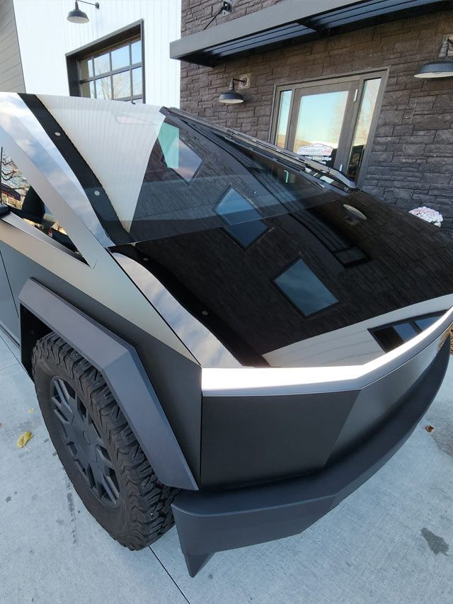 A person wearing black gloves is polishing a black car