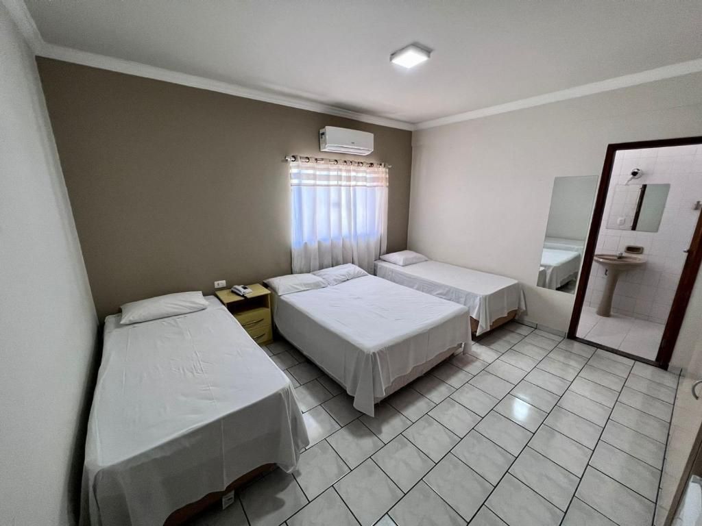 Um quarto com três camas, uma pia e uma janela.