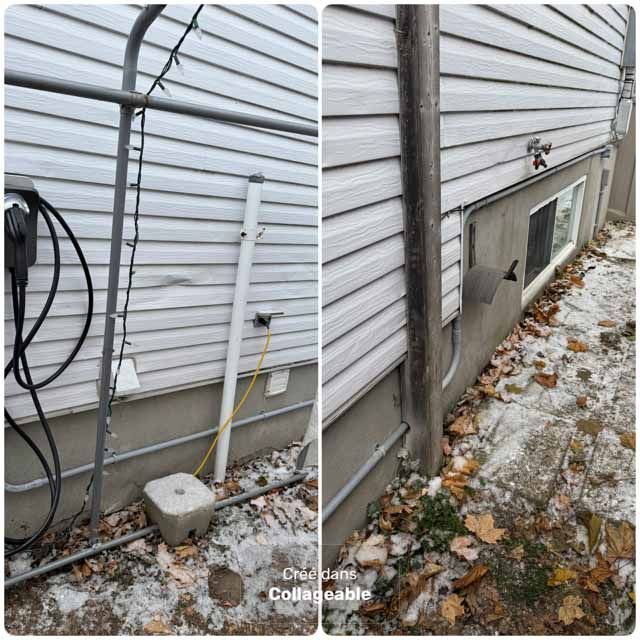 Extérieur d'une maison avec un bardage blanc et des fondations en béton ; la neige et les feuilles mortes sont visibles.