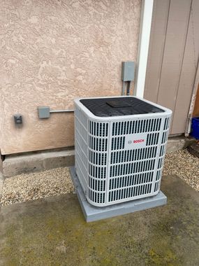 An air conditioner is sitting on top of a roof next to solar panels | Heating & Airflow