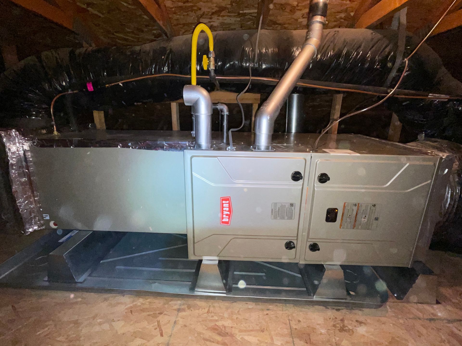 A large air conditioner is sitting in the attic of a house.